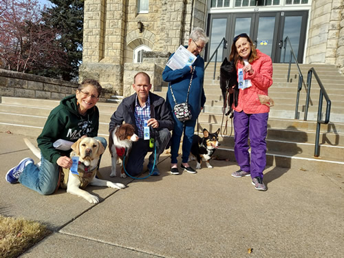 Four adults with their dogs holding Canine Good Citizen Urban Test ribbons and certificates
